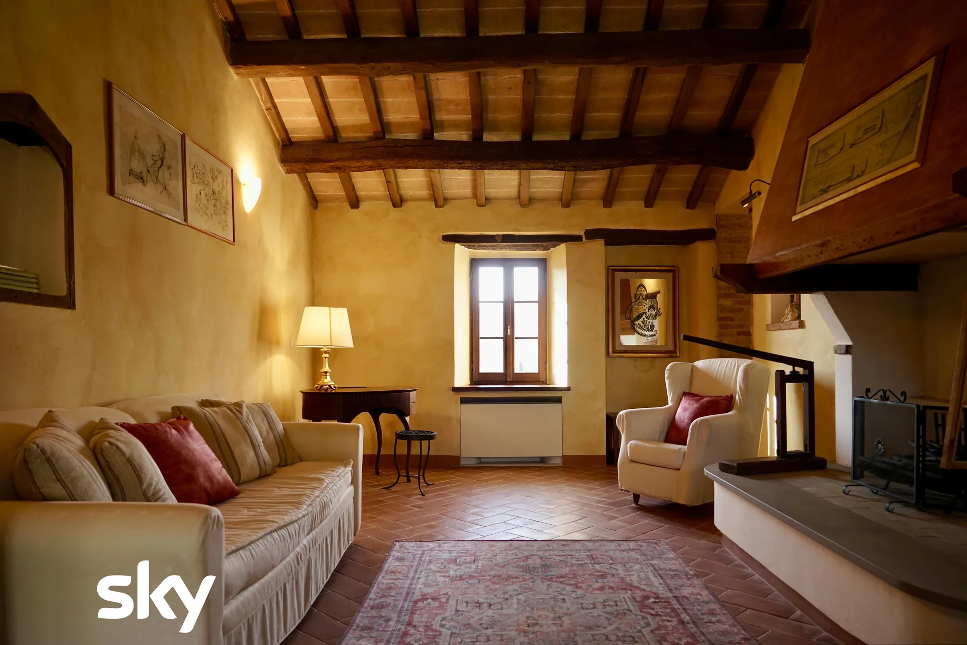 Il salotto con il camino e le travi a vista, dove si aspetta il check-in