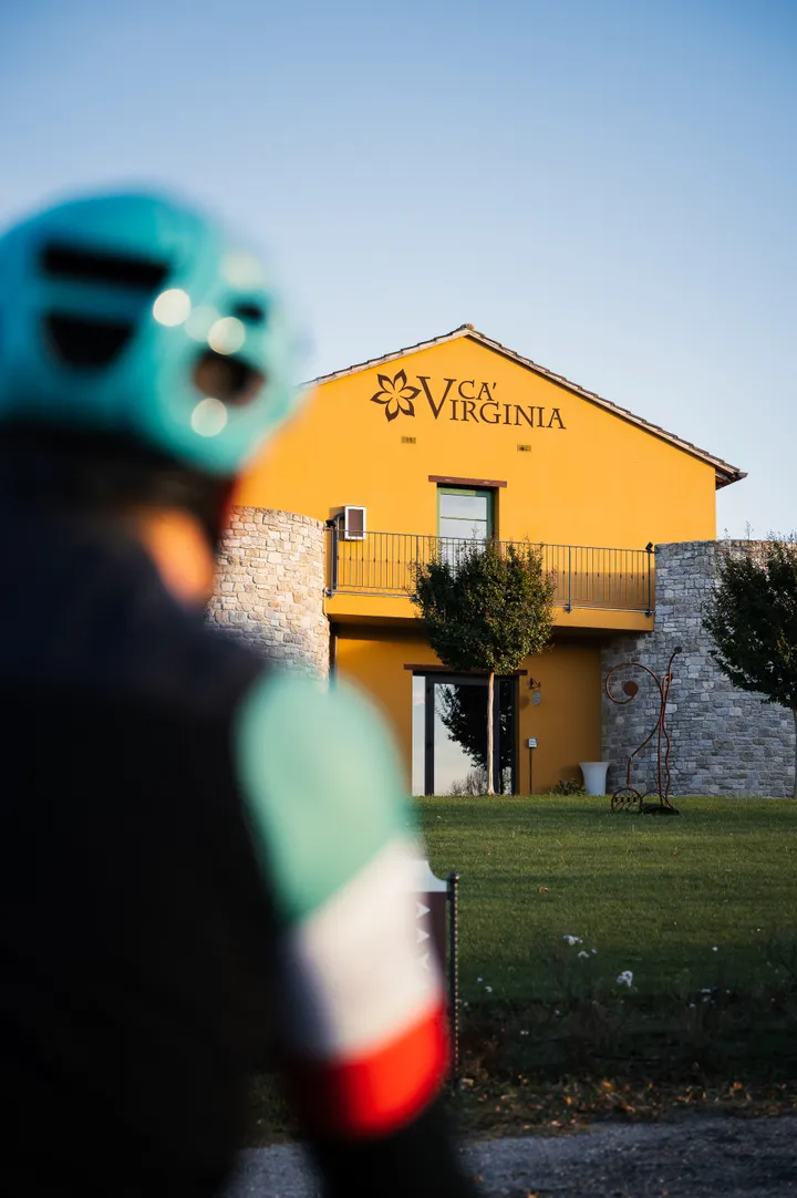 A cyclist in front of the yellow farmhouse of Ca' Virginia