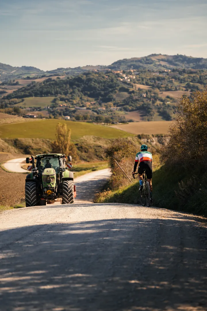 Cyclist on a white gravel road through the Montefeltro hills