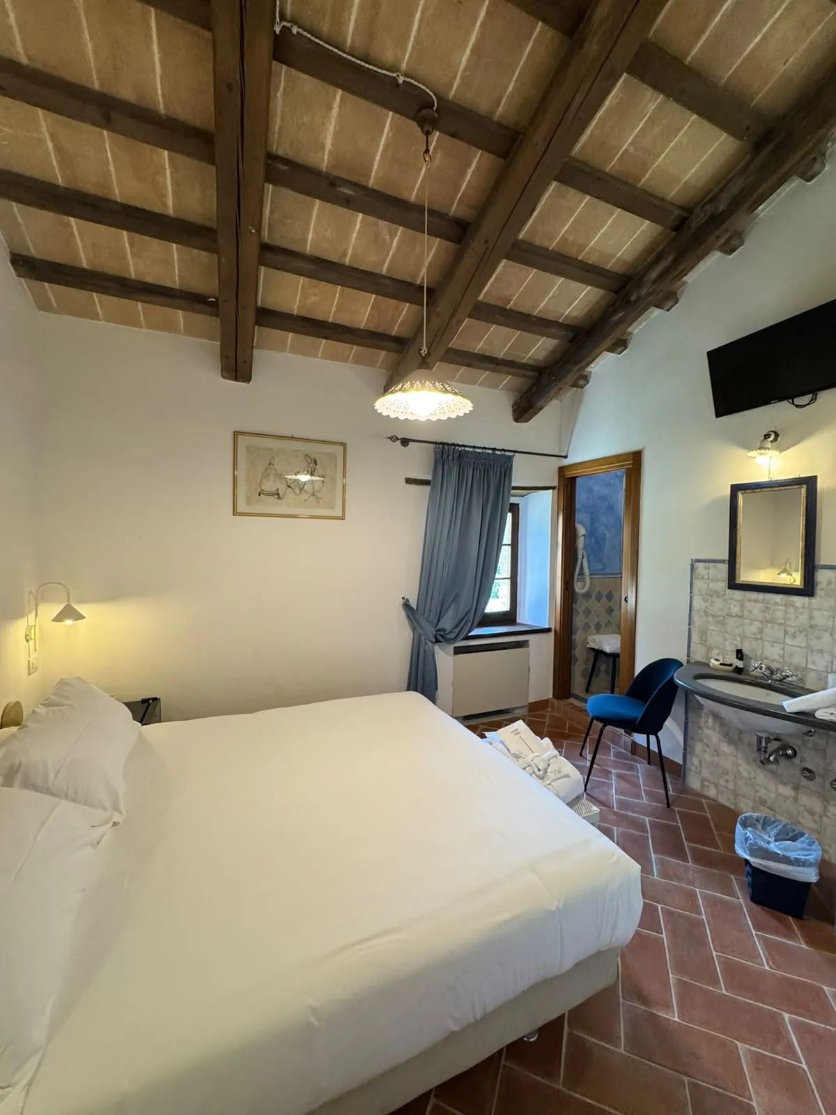 Camera Rurale con letto matrimoniale, soffitto a travi, lavabo con piastrelle e pavimento in cotto