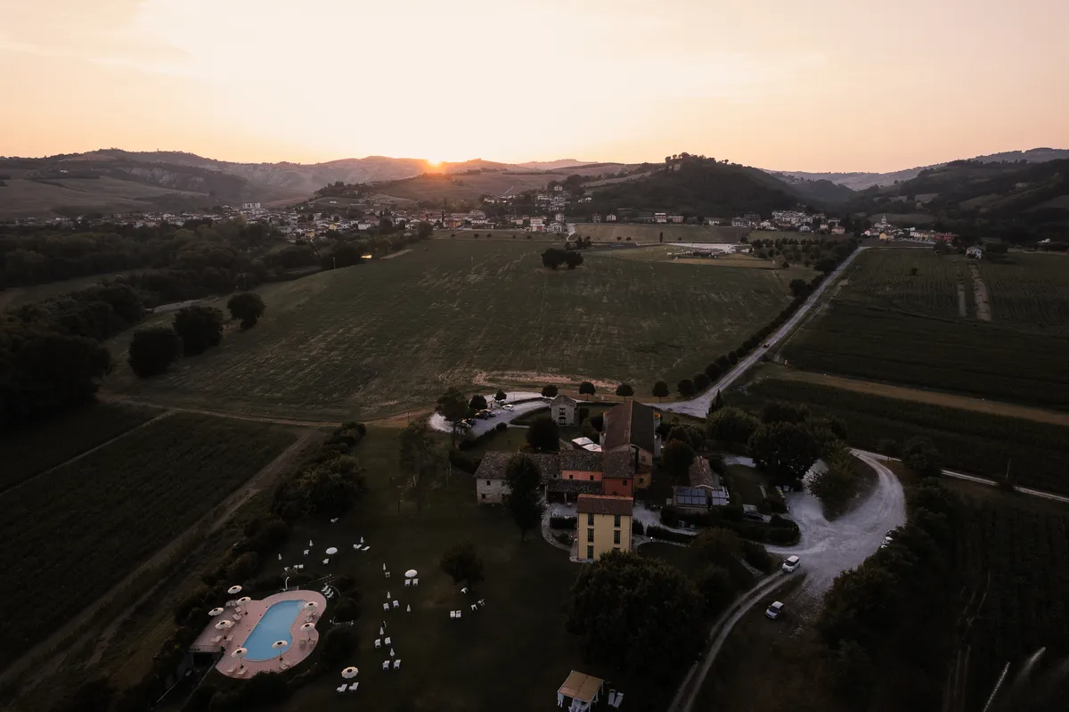 Il casale di Ca' Virginia al tramonto, visto dall'alto nella Valle del Foglia con Borgo Massano sullo sfondo