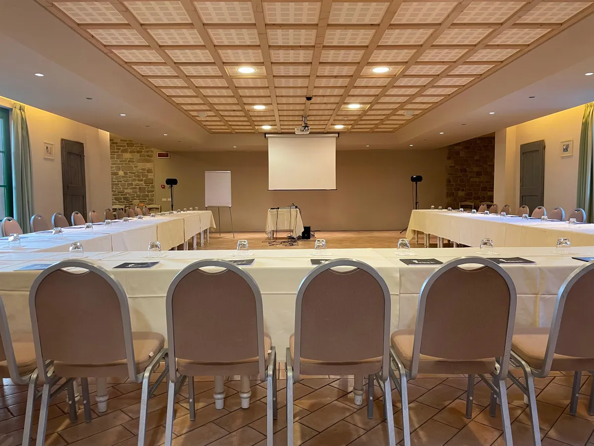 La Sala Il Convivio allestita a ferro di cavallo per un meeting, con schermo di proiezione e lavagna a fogli mobili